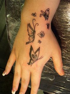 a woman's hand with tattoos on it and butterflies flying around the wrist area