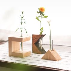 three wooden vases with flowers in them on top of a table next to each other