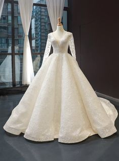 a white wedding dress on display in front of windows