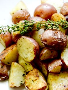 roasted potatoes with rosemary garnish on a white plate