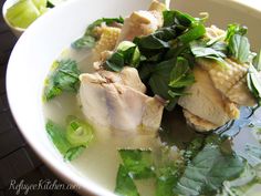 a white bowl filled with meat and greens on top of a table next to a cup