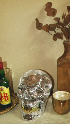 there is a glass skull next to a bottle and a candle holder on the table