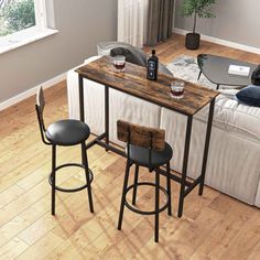 a living room filled with furniture and a wooden table topped with two stools next to a white couch