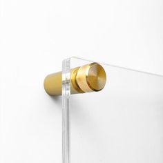 a pair of gold ear buds sitting on top of a glass block in front of a white wall