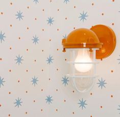 an orange light is on the wall next to a blue and white star patterned wallpaper