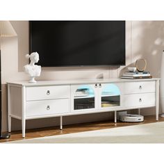 a white entertainment center with two drawers and a flat screen tv mounted on the wall