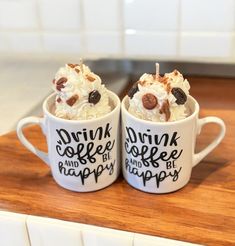 two coffee mugs filled with ice cream and toppings on top of a counter