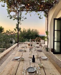 an outdoor dining table with wine bottles and glasses on it