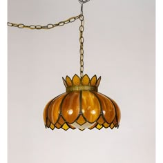 a light fixture hanging from a chain on a white wall