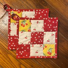 two red and yellow placemats with cherries on them sitting on a wooden floor