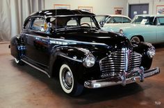 an old black car parked in a garage