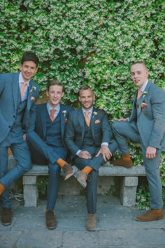 three men in suits are sitting on a bench