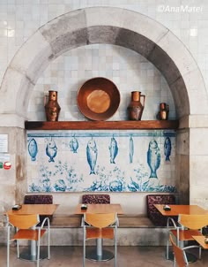 a restaurant with blue and white tiles on the wall, wooden tables and chairs in front of them