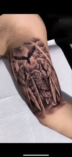 a man's arm with an angel and cross tattoo on the left side of his leg