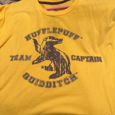 a yellow t - shirt with the words mufflepuff team captain quiddit cat on it