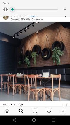 an image of a restaurant setting with chairs and plants on the wall, along with hanging tires