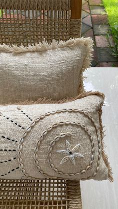 two decorative pillows sitting on top of a wicker chair