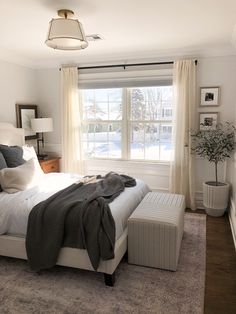 a bedroom with a bed, window and rug on the floor in front of it