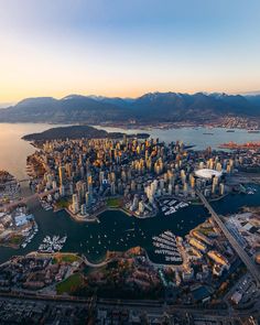 an aerial view of a large city with mountains in the background and boats on the water