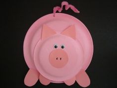 a pink pig toy hanging on a black wall with two birds perched on it's back