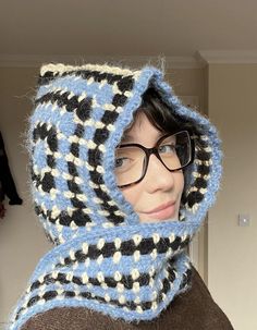 a woman wearing glasses and a knitted hoodie with a scarf around her neck