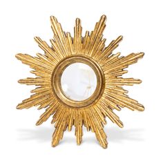 a gold sunburst shaped mirror sitting on top of a table