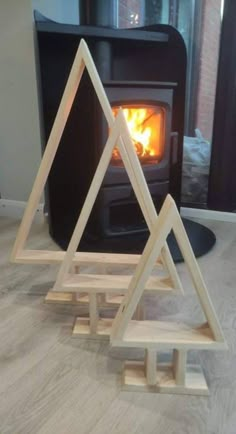 three wooden pyramids sitting on the floor in front of an open fire place with wood burning