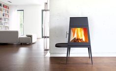 a stove in the middle of a living room with wood burning on it's side