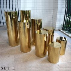 gold colored vases are lined up on the floor