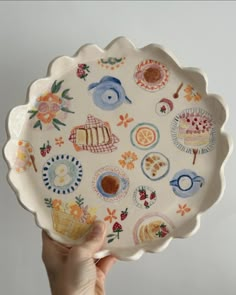 a hand holding a plate with many designs on it