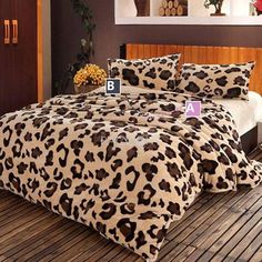 a leopard print comforter set on a bed in a room with wood flooring