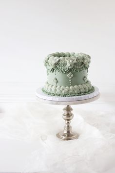 a green cake sitting on top of a metal stand