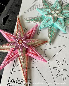 two star shaped ornaments sitting on top of a piece of paper