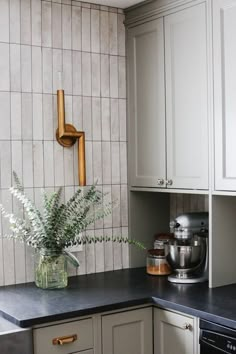 a kitchen with white cabinets and black counter tops, including a potted plant in the corner