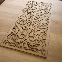 an intricately carved wooden design on a table top with a wood flooring board in the background