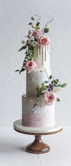 a three tiered wedding cake with pink flowers on the top and white icing