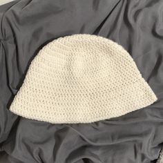 a white crocheted hat laying on top of a blanket