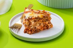 a piece of lasagna on a plate with a fork and napkin next to it