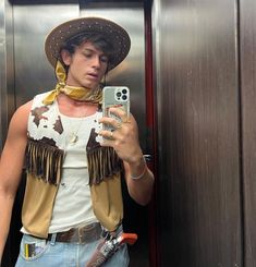 a man wearing a cowboy hat taking a selfie in an elevator with his cell phone