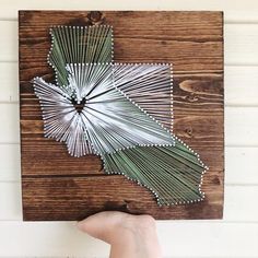 a person holding up a piece of art made out of metal rods and wood planks