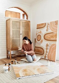 a woman is sitting on the floor painting