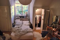 a bedroom with an unmade bed and lots of clothes