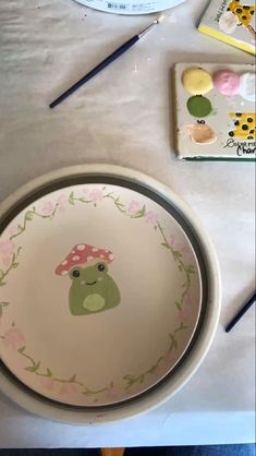 two plates with designs on them sitting on a table next to some paintbrushes