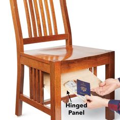 a person is holding a passport in front of a wooden chair with the seat removed