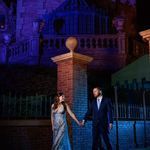 a man and woman standing next to each other in front of a building at night