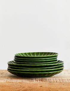 a stack of green plates sitting on top of a wooden table