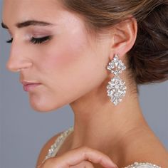 a woman in a white dress wearing earrings with flowers on it's back side