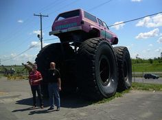 two men standing next to a giant monster truck