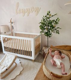 a baby laying in a crib next to a potted plant