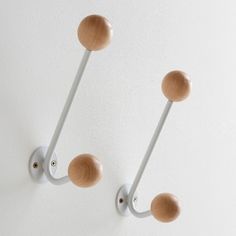 two wooden knobs mounted to the side of a white wall next to each other